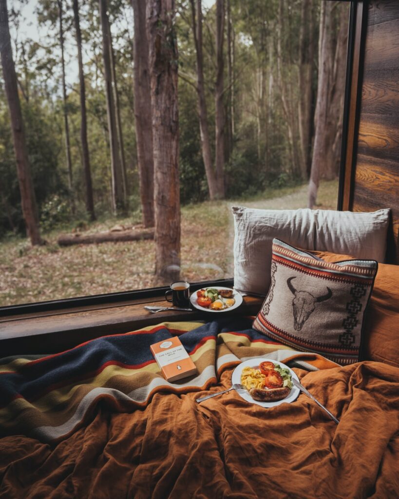 a bed with a tray of food on it next to a window